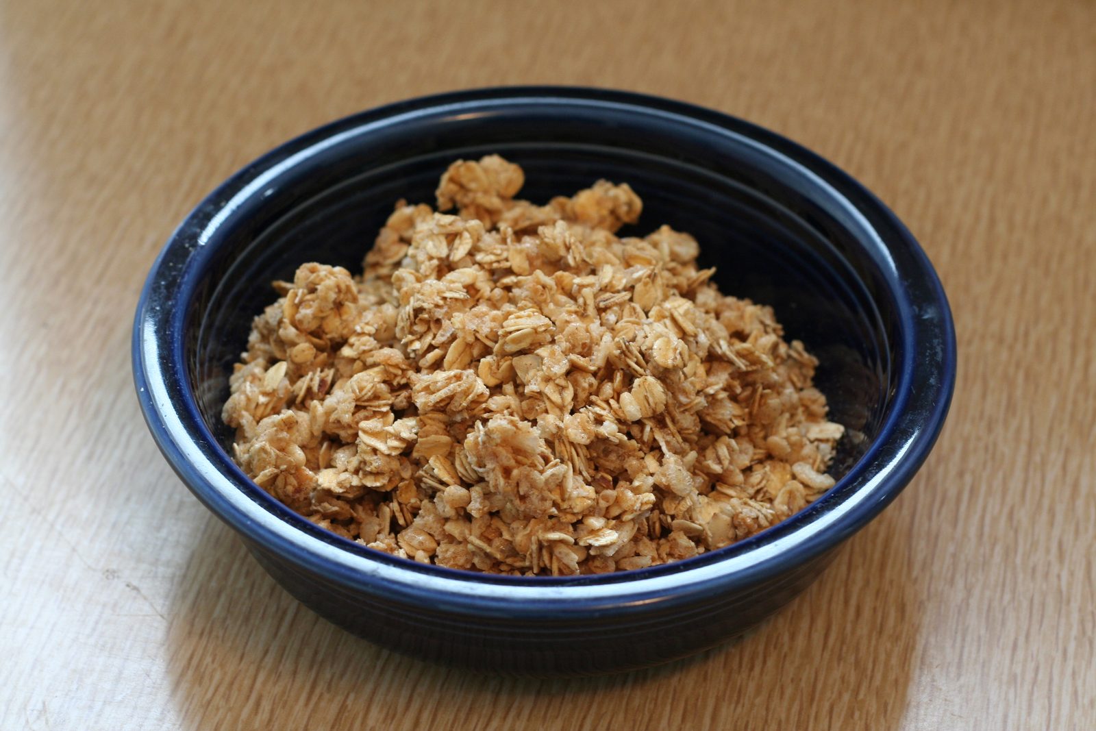 深藍色碗裡裝著一堆穀麥脆塊，放在木桌上