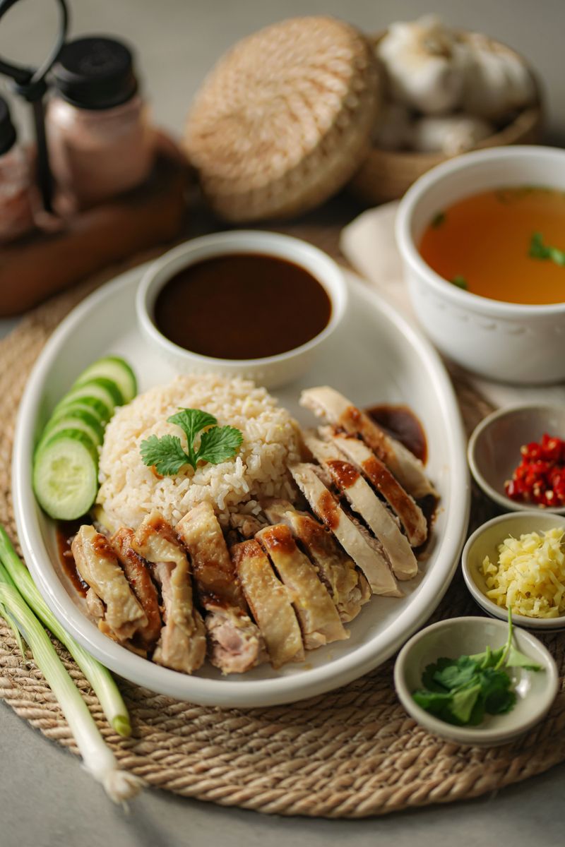 A plate of Hainanese chicken rice with dipping sauces and soup