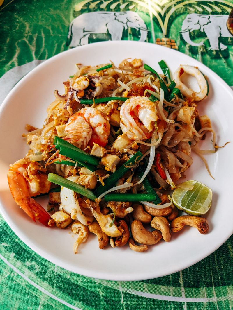A plate of pad thai noodles with shrimp and crushed peanuts