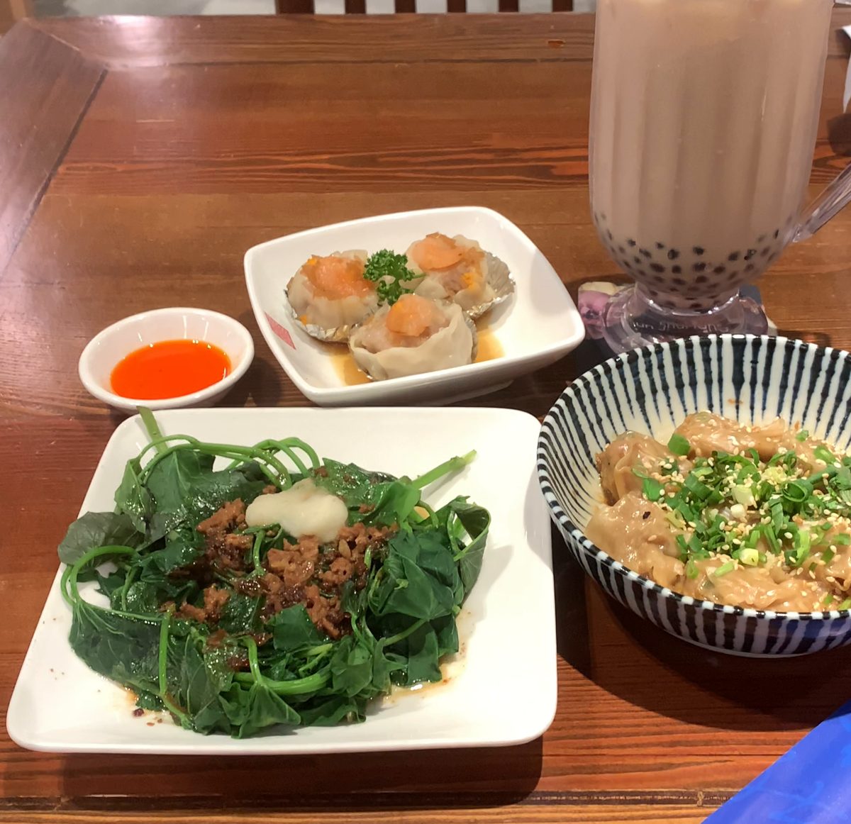A table for two at a Taiwanese tea house: bubble milk tea, stir-fried sweet potato leaves with minced pork, a cold tofu skin salad, and a plate of three steamed siu mai