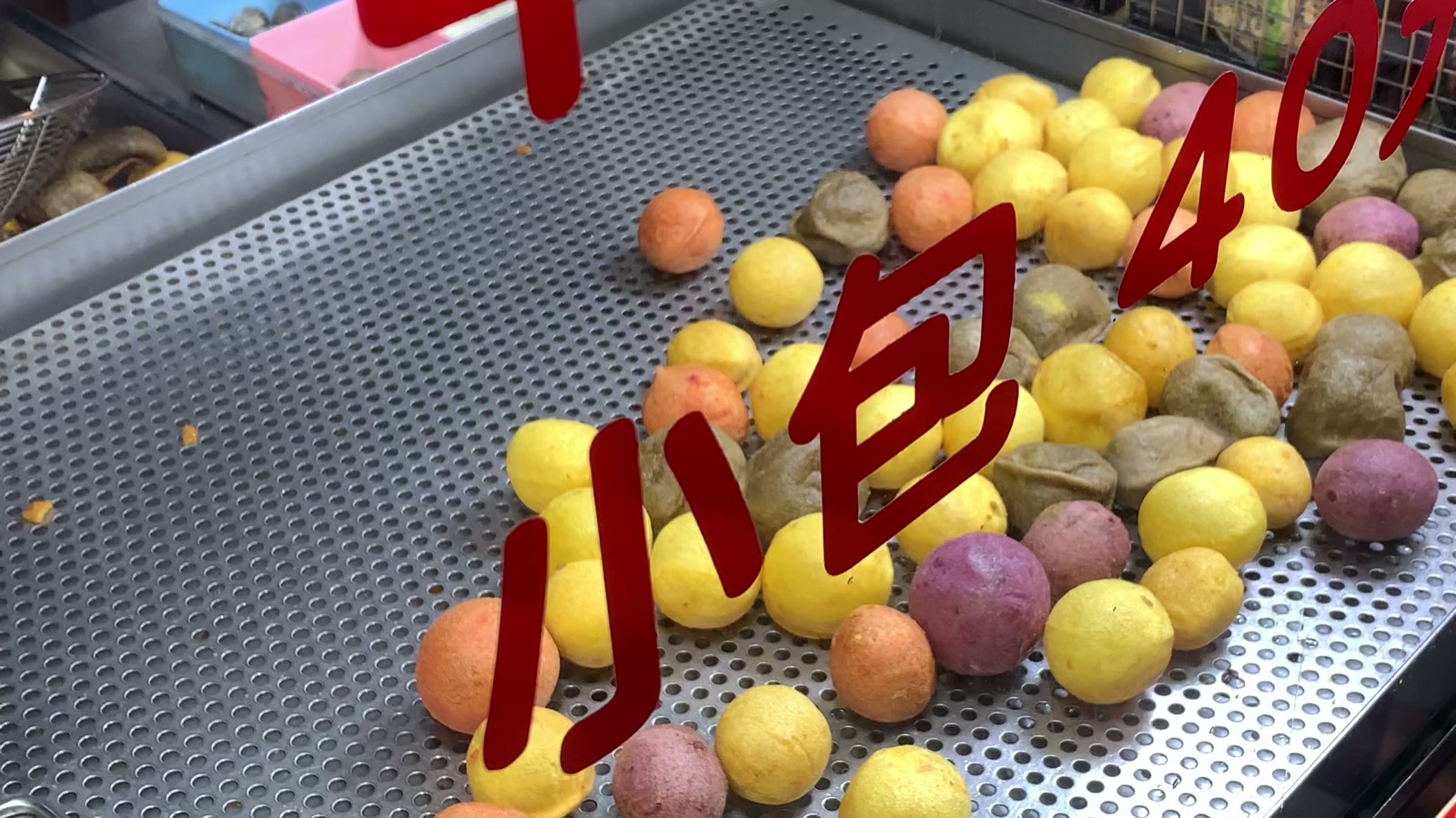 Fried sweet potato balls (地瓜球) draining on a tray at a Taiwanese street food stand