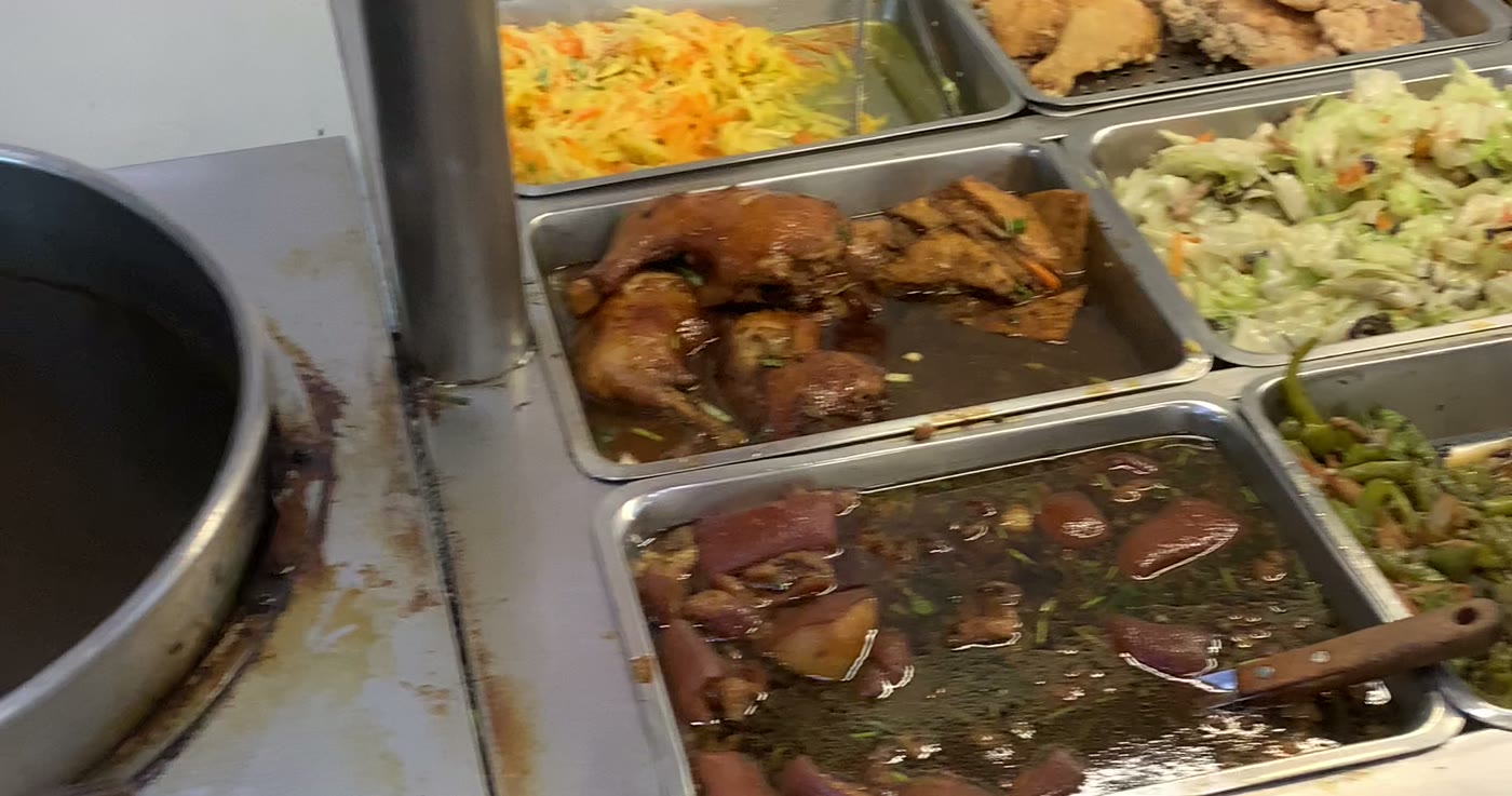 A Taiwanese 自助餐 counter: steel trays of braised chicken, braised tofu skin, shredded cabbage, fried chicken and stir-fried peppers