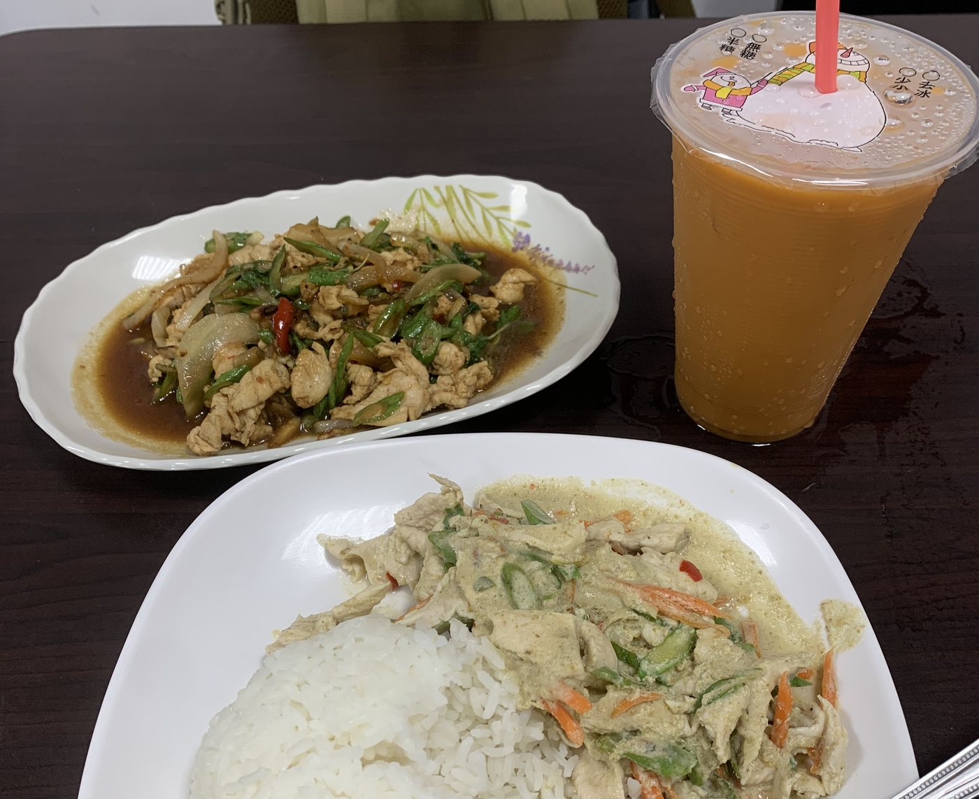 泰式小吃店的一桌菜：一盤打拋雞、一盤綠咖哩雞配白飯，還有一大杯泰式奶茶